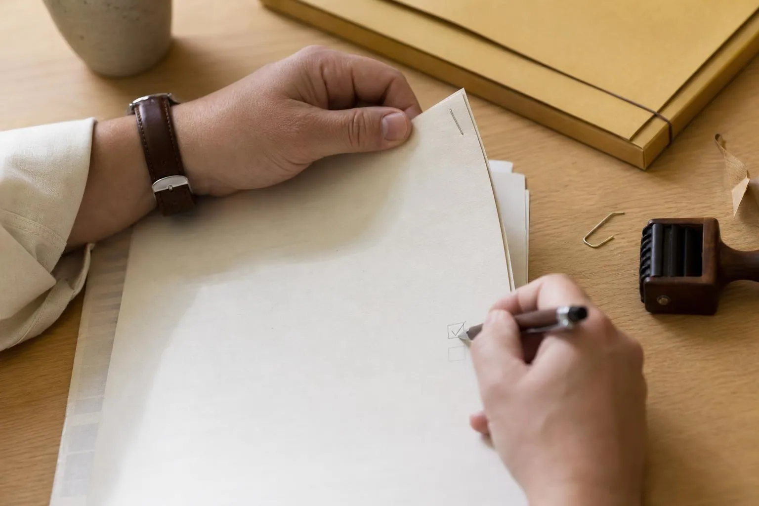 Mains cochant au stylo les lignes d’une liasse de contrôle posée sur un plan de travail clair